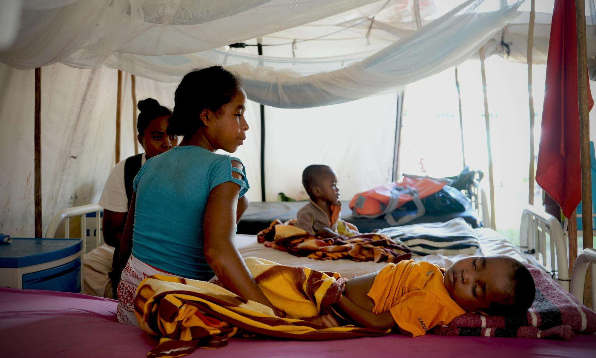 Mother sits beside her child receiving treatment for malaria.